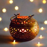 Antique metal candle stand with round mesh design and golden oxidized polish, casting beautiful light patterns when lit.