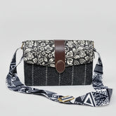 Women’s black and white floral sling bag with a textured woven fabric body and premium black PU leather accents.