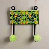 A decorative Blue Pottery cloth hanger with two hooks for wall mounting.