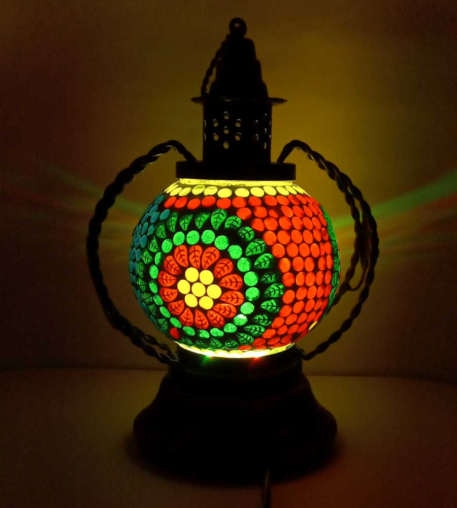 A decorative table lamp with a mosaic pattern, made from glass, wood, and metal.