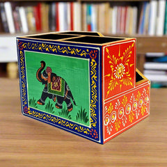A hand-painted wooden pen holder with an elephant on the front and floral designs on the sides.