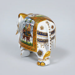 Side view of a white wood elephant showing the intricate gold-bordered Mughal saddle design.