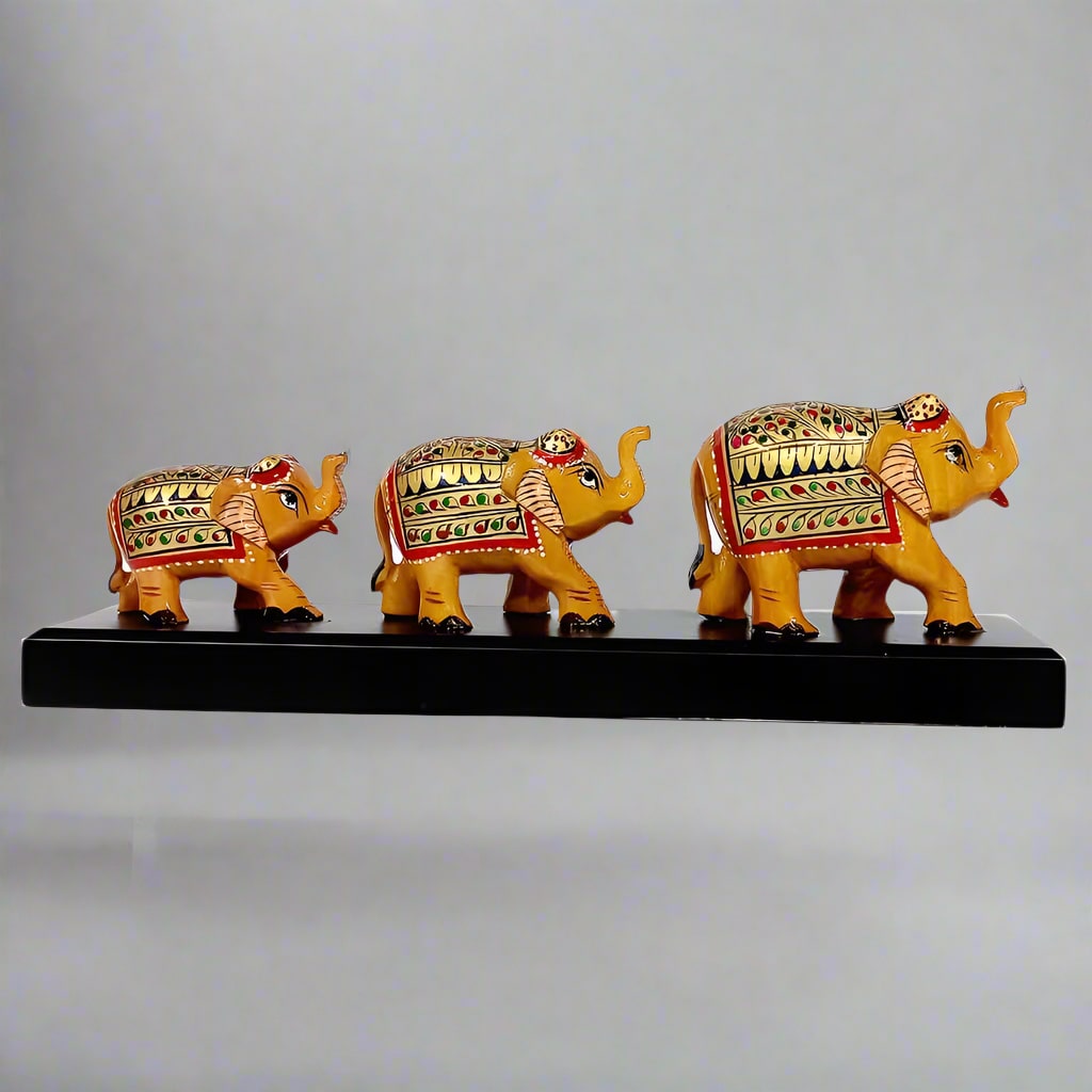 Set of three hand-painted wooden elephants of varying sizes standing on a decorative wooden bridge.