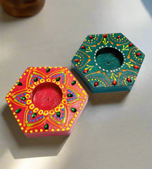 A handcrafted pair of wooden tea light holders, painted with intricate designs.
