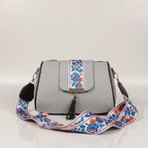 Close up of leather tassel and magnetic closure on a printed jacquard sling bag