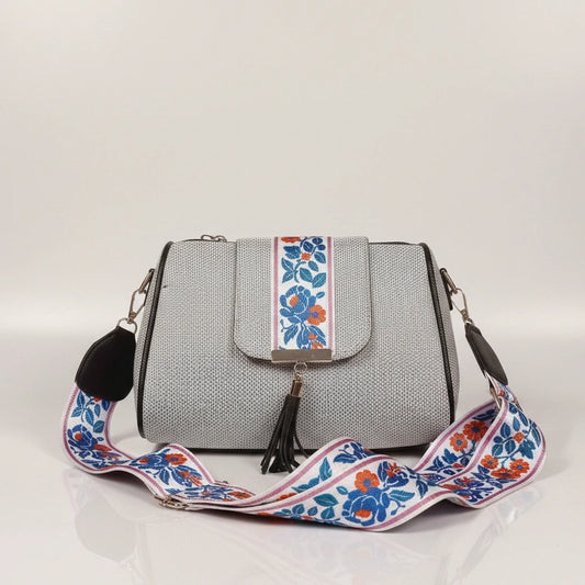 Close up of leather tassel and magnetic closure on a printed jacquard sling bag