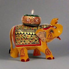 Decorative wooden candle holder shaped like a long trunk elephant, adorned with intricate traditional colors and hand art.