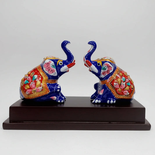 Two colorful Meenakari painted sitting Appu elephants on a polished wooden platform for home decor.