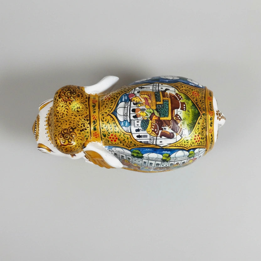 Intricate Mughal floral hand-painting on the saddle of a white and gold wooden elephant.