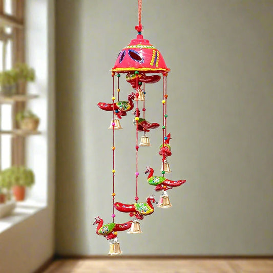 A hand-painted paper mache toran with seven peacocks and golden bells.