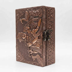 Closeup of embossed Radha Krishna copper artwork and floral border on wooden box lid.