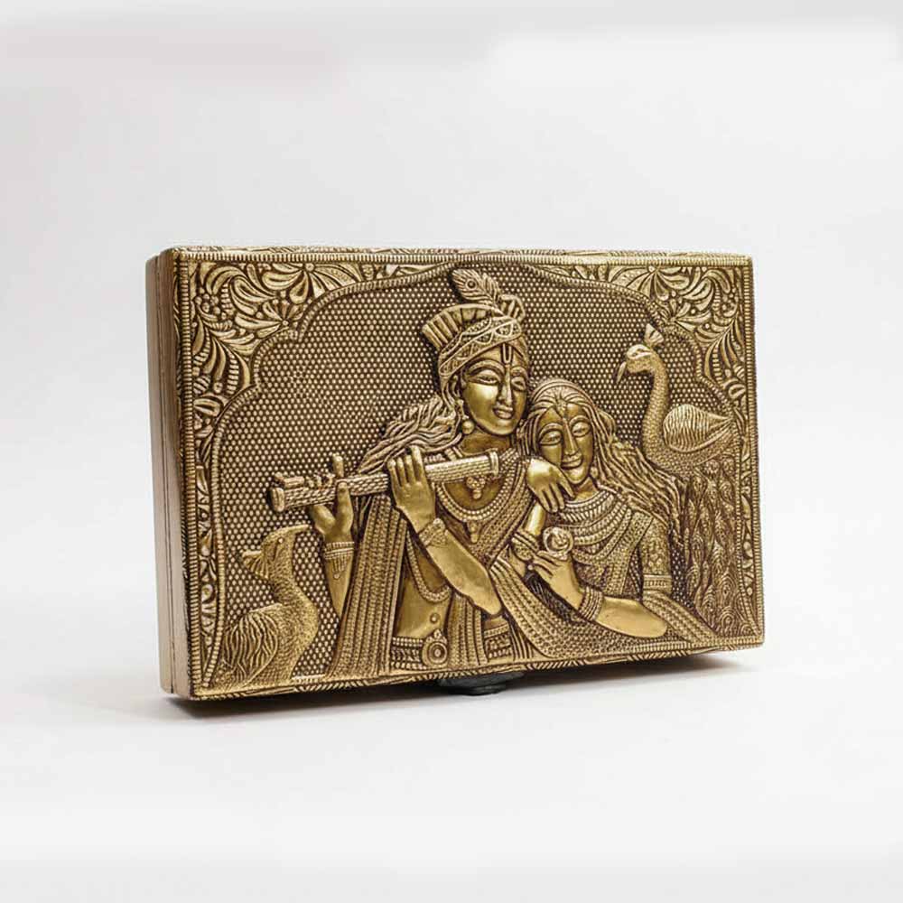 Closeup of intricate golden embossed Radha Krishna design and floral border on box lid.