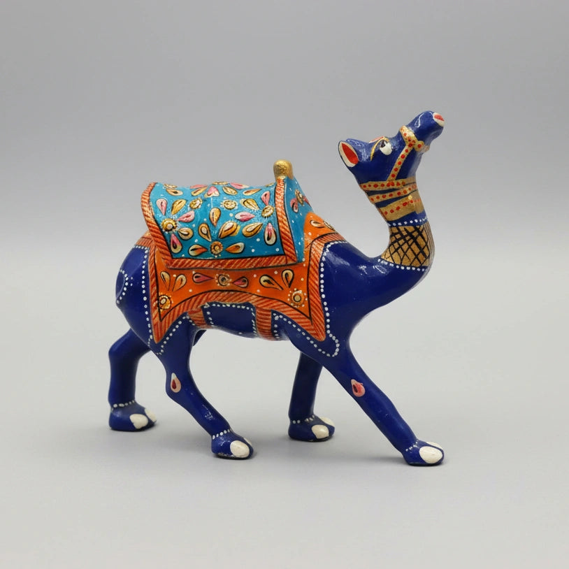 A high-necked metal camel idol with intricate blue enamel and hand-painted Meenakari saddle, displayed as a sophisticated office desk centerpiece.