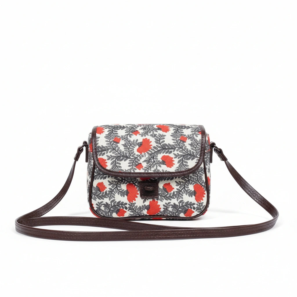 Front view of a small floral print sling bag with button closure and top handle