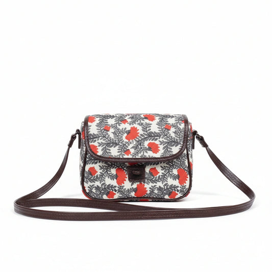 Front view of a small floral print sling bag with button closure and top handle