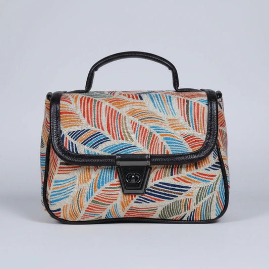 Front view of a small floral print ethnic crossbody bag with button closure.