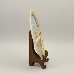 Artisanal marble plate with Taj Mahal painting displayed on an elegant dark wood stand, perfect for luxury home or office decor.