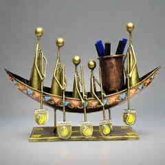 A tribal art metal pen holder with a boat design and a tribal man riding on it.