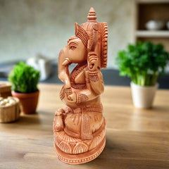 Wooden Ganesh idol seated on lotus, intricately carved for spiritual decor.