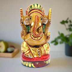 A wooden Ganesh murti with laddoos in one hand, considered best for worship in a home temple.