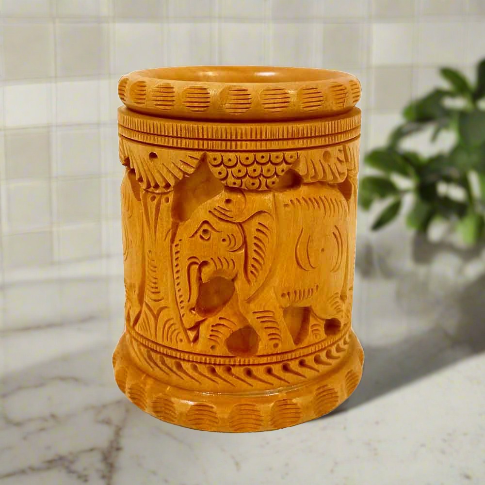 An amazing wooden pen stand with intricate carvings of elephants and tree plants.