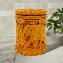 An amazing wooden pen stand with intricate carvings of elephants and tree plants.