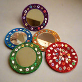 A decorative wooden pocket mirror adorned with beautiful lac/lakh work and glass beads.