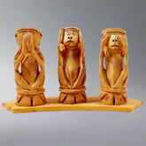Gandhi-inspired wooden monkey carving with eyes closed, see no evil pose.