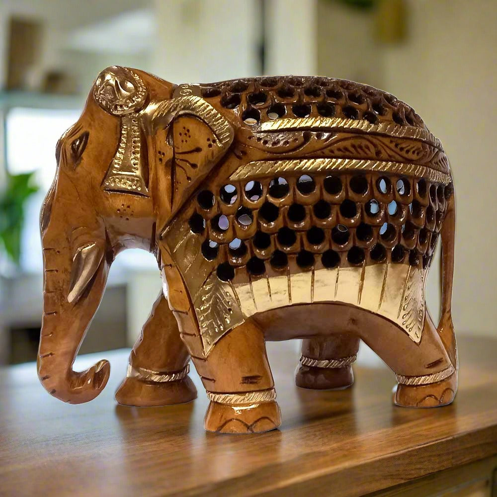 A hand-carved wooden elephant figurine with a short trunk and beautiful carvings on its body.
