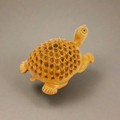 Hand-carved wooden tortoise statue with lattice work on back, enhancing pooja room ambiance.
