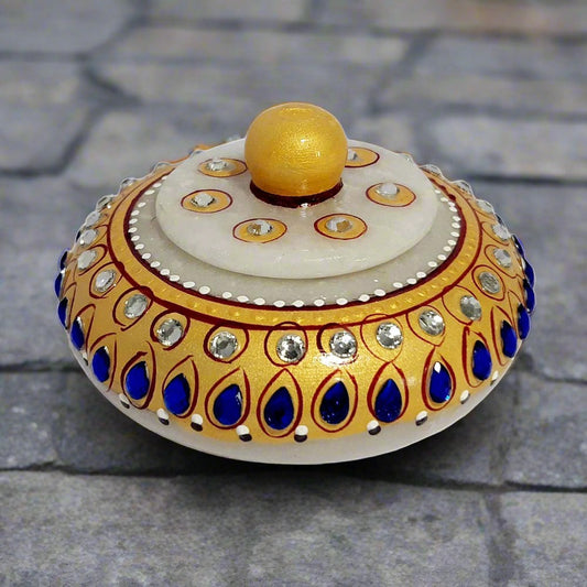 Hand-carved round marble kumkum box adorned with hand painting and studded with blue and white kundan.