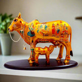 A handcrafted, gold-painted Kamdhenu cow with a calf, a divine showpiece for worship and decor.