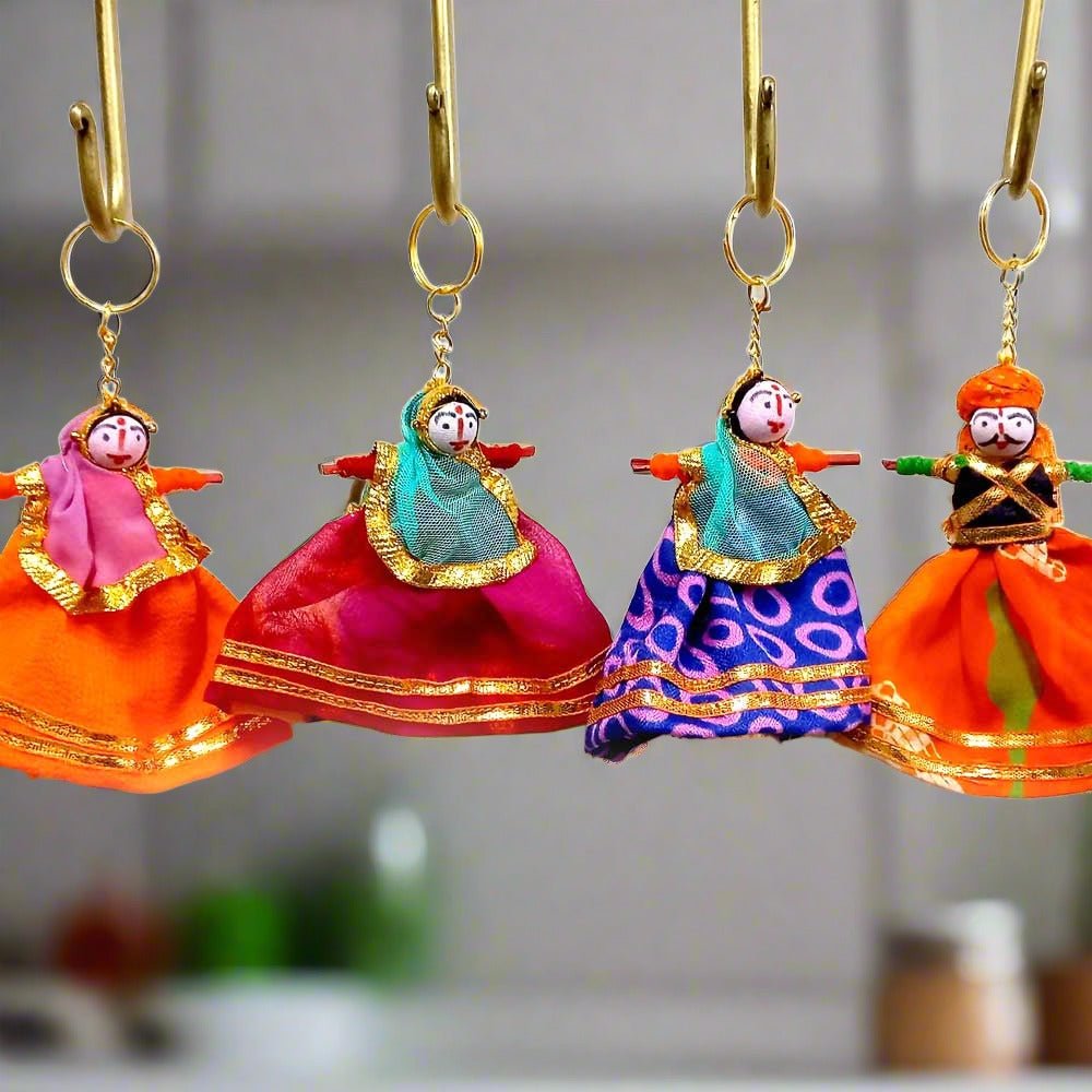 A handmade key ring of a fabric and wooden Rajasthani puppet couple, with a fine quality golden ring.