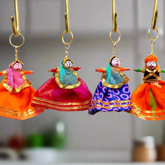 A handmade key ring of a fabric and wooden Rajasthani puppet couple, with a fine quality golden ring.