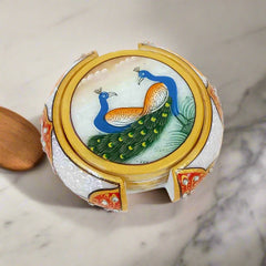Handmade marble coasters with intricate peacock paintings, round shape, and decorative embossed holder.