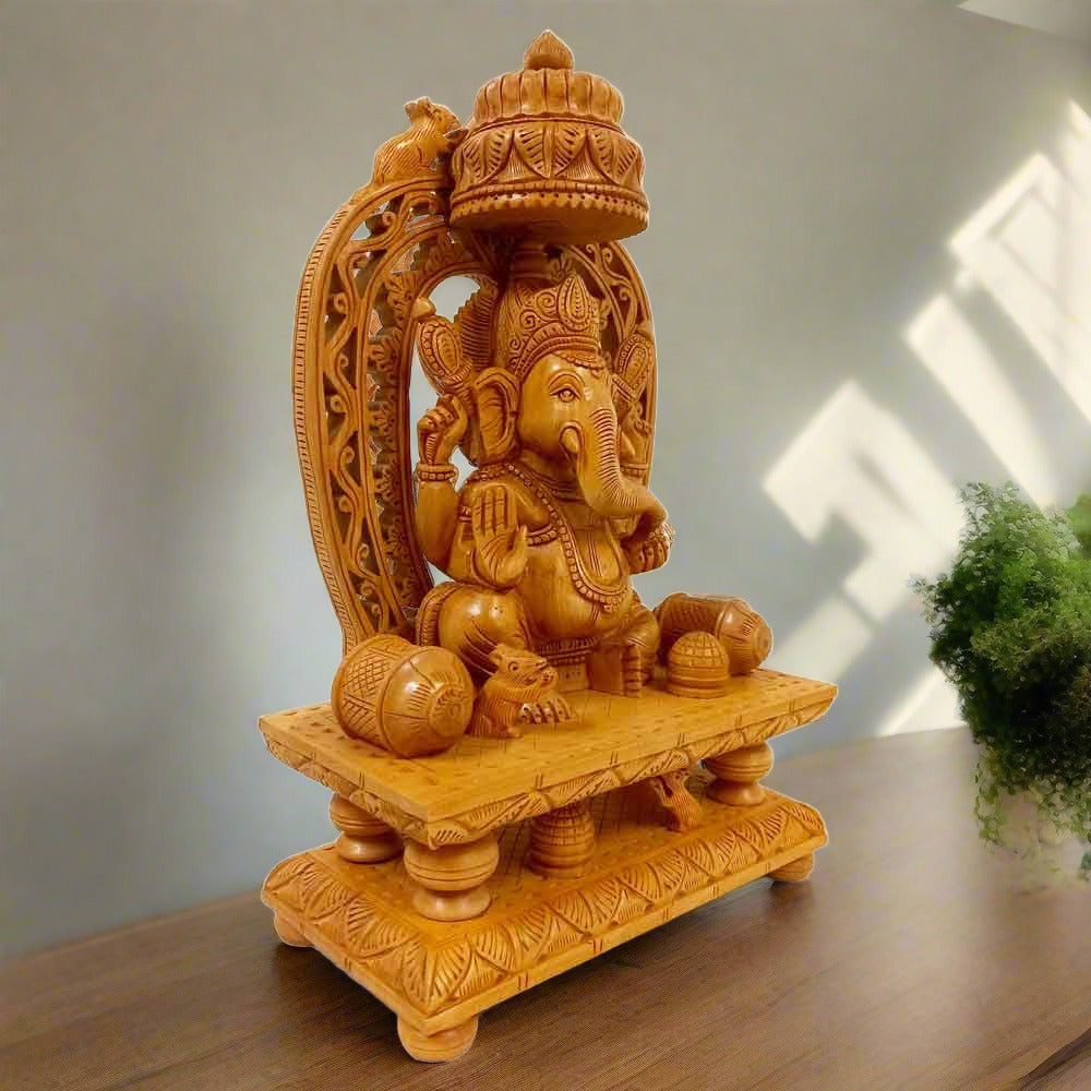 A high-quality wooden Ganeshji statue seated on a throne with a mouse and prasad in front.
