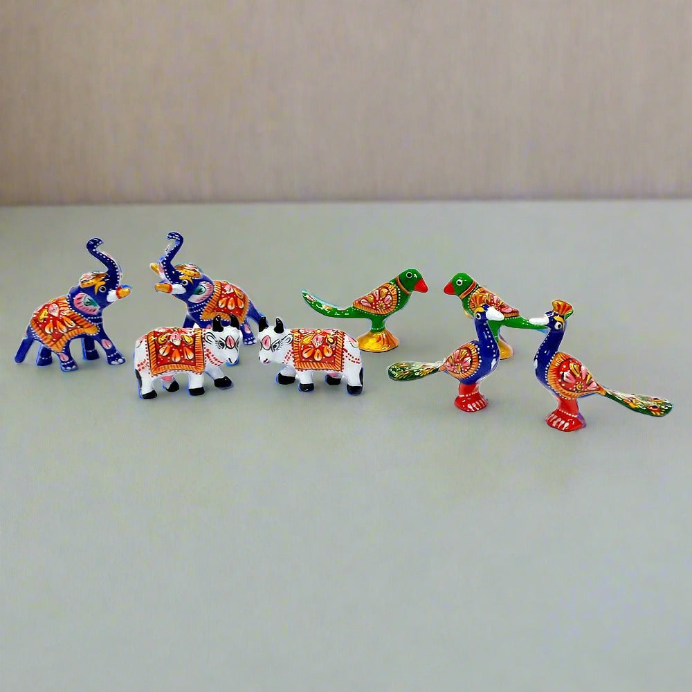 A set of meenakari hand-painted temple decor toys, including a sacred cow and other animals.