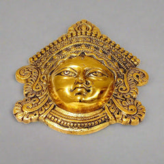 A golden metal Durga face, a symbol of strength and courage, perfect for a pooja room wall.