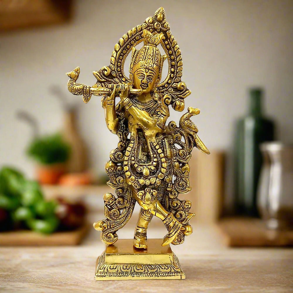 A beautiful metal Krishna idol, standing and playing the flute with a long garland.