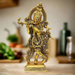 A beautiful metal Krishna idol, standing and playing the flute with a long garland.