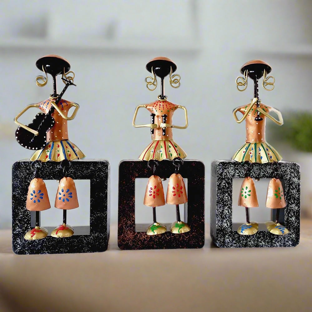 A set of 3 metal musical dolls sitting on a wooden plank, a beautiful showpiece.