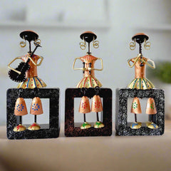 A set of 3 metal musical dolls sitting on a wooden plank, a beautiful showpiece.
