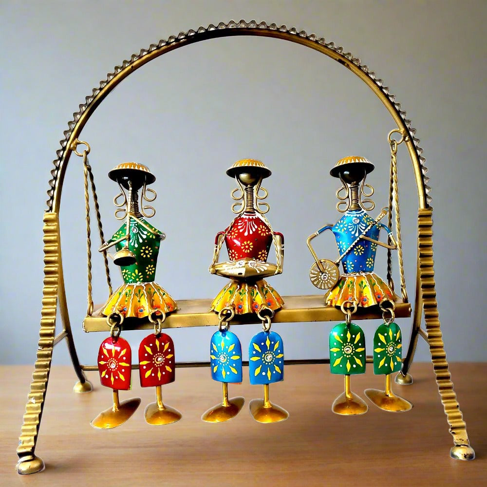 A beautiful metal Rajasthani jhula doll set with three musician dolls playing instruments.