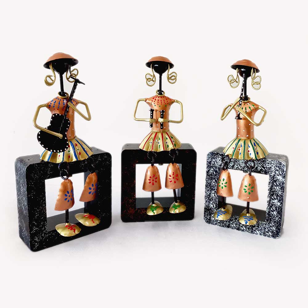 A musical doll showpiece featuring three dolls playing instruments on a wooden plank.