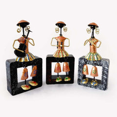 A musical doll showpiece featuring three dolls playing instruments on a wooden plank.