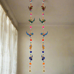 A decorative parrot toran made from papermache, decorated with bells, pom-poms, and beads.