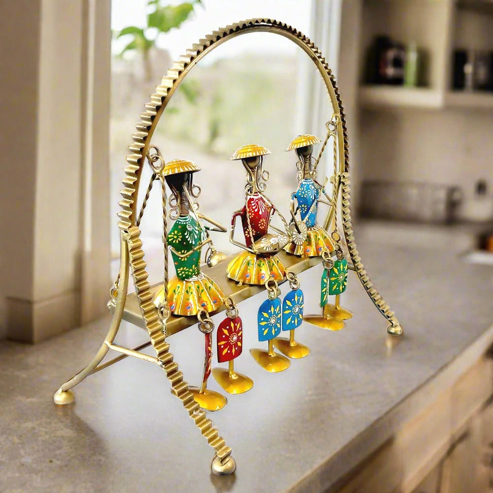 A beautiful example of Rajasthani art with three dolls swinging on a jhula, with moving legs.