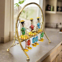 A beautiful example of Rajasthani art with three dolls swinging on a jhula, with moving legs.