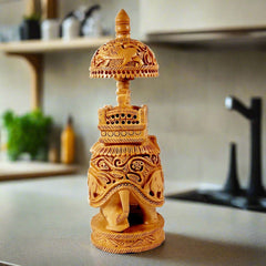 A round-shaped wooden elephant sculpture with a beautiful carving and a round umbrella over the palanquin.