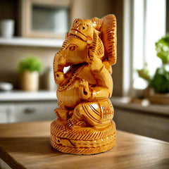 Side view of carved wooden Ganesh statue in blessing pose for pooja.